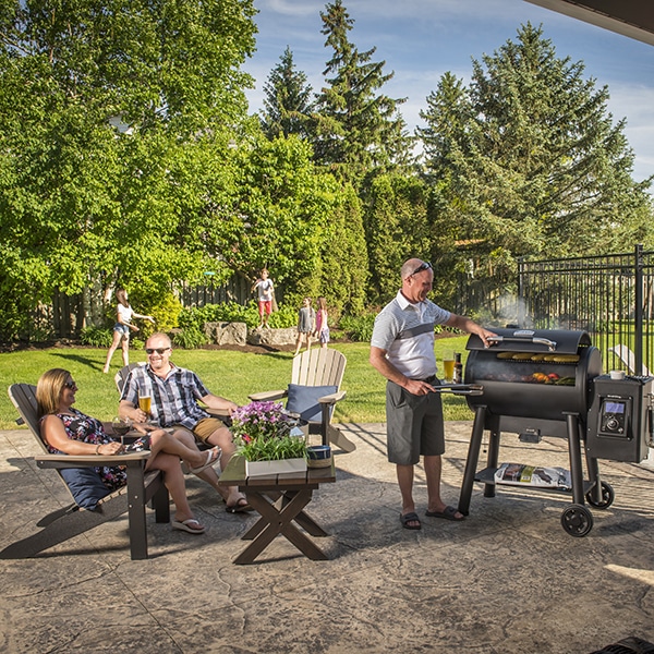 Famille qui profite de leur espace extérieur avec leur barbecue Broil King pellet regal 400