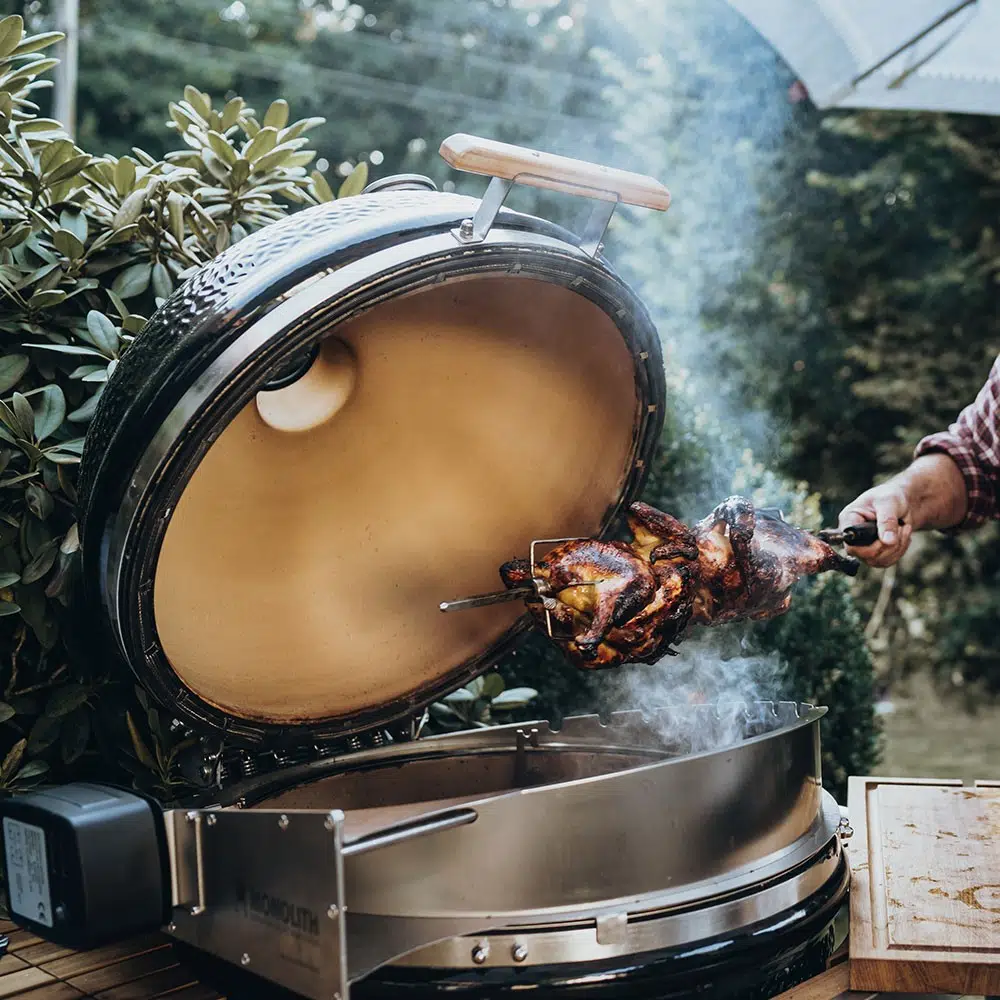 Homme qui fume son poulet à la broche à l'aide de son kamado Monolith